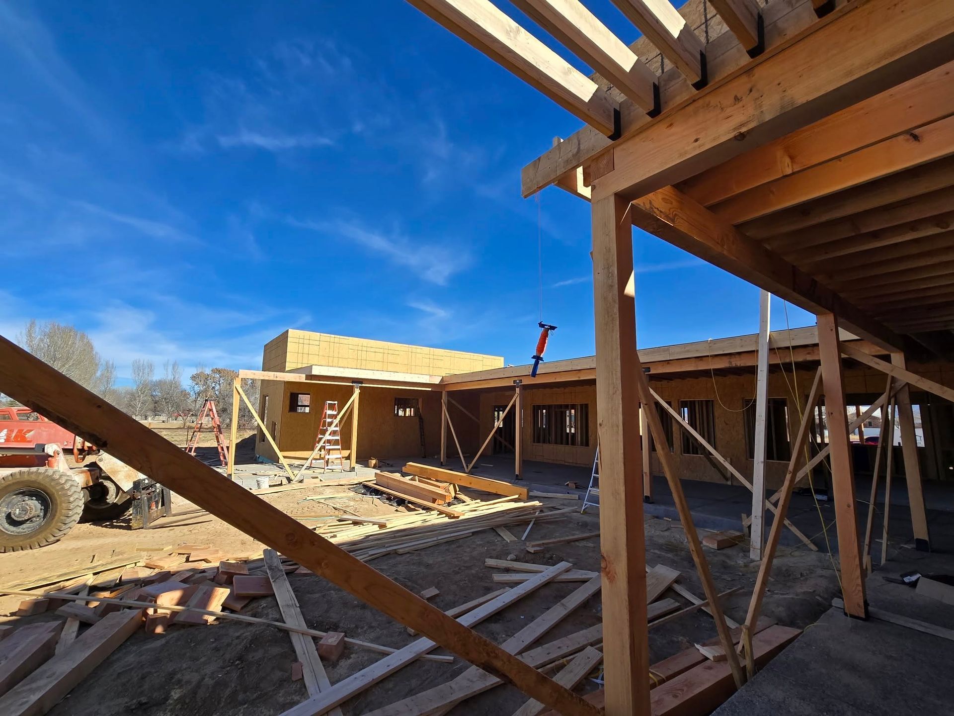 Partially built house with exposed framing and wooden beams under a bright blue sky