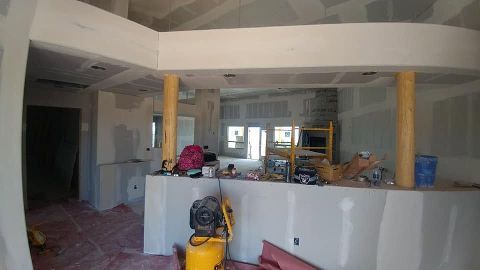 Partially renovated kitchen with unfinished walls, cabinets, tools, and construction materials on the counter