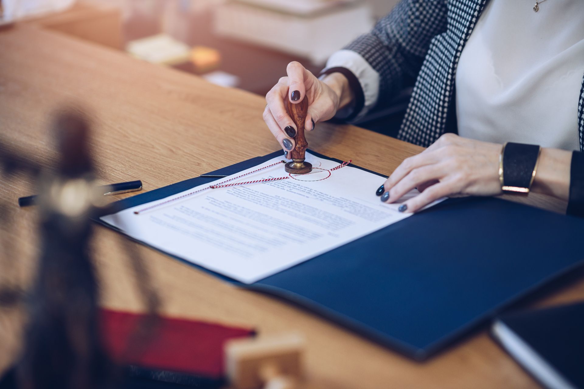 Person stamping a document on a desk, a legal symbol on the side, inside a blue folder.