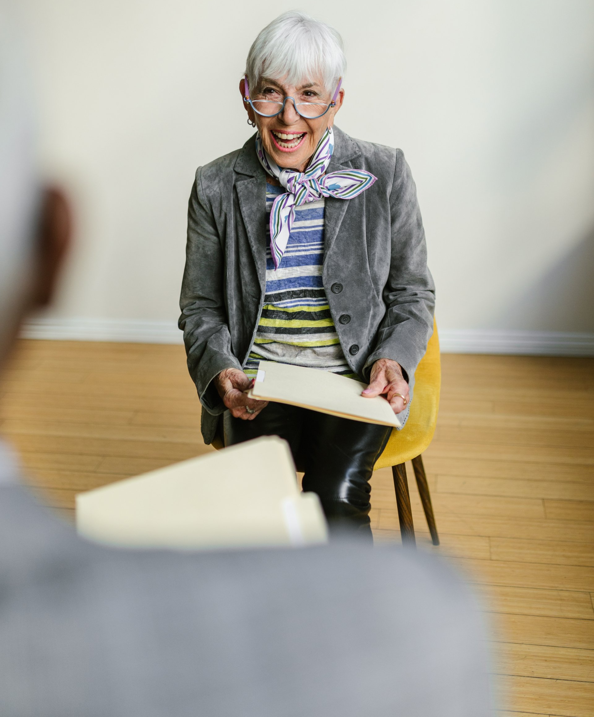 An older woman is sitting in a chair holding a piece of paper.