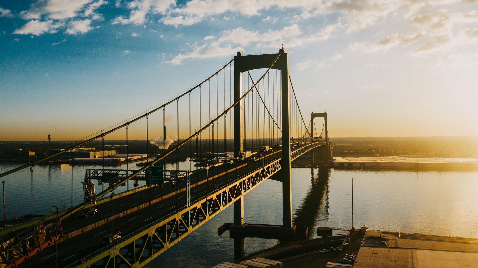 An aerial view of a bridge over a body of water at sunset.
