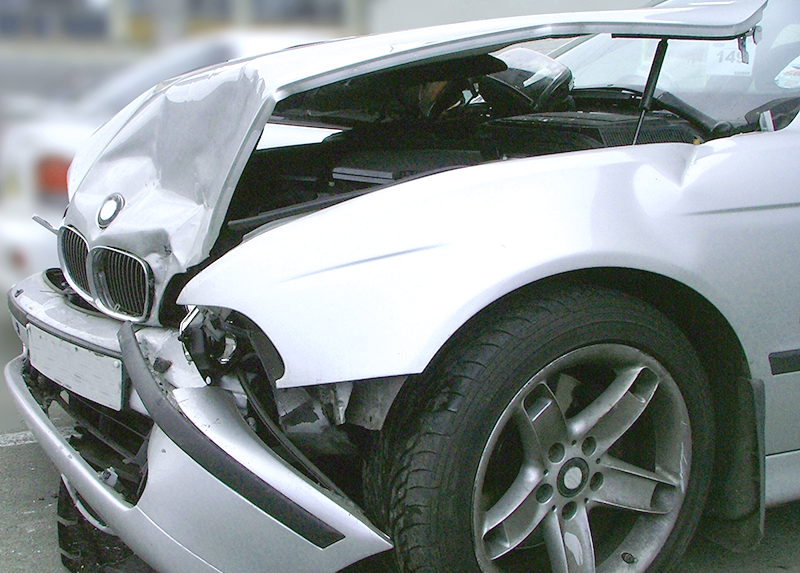 A silver car with its hood open has been damaged in an accident