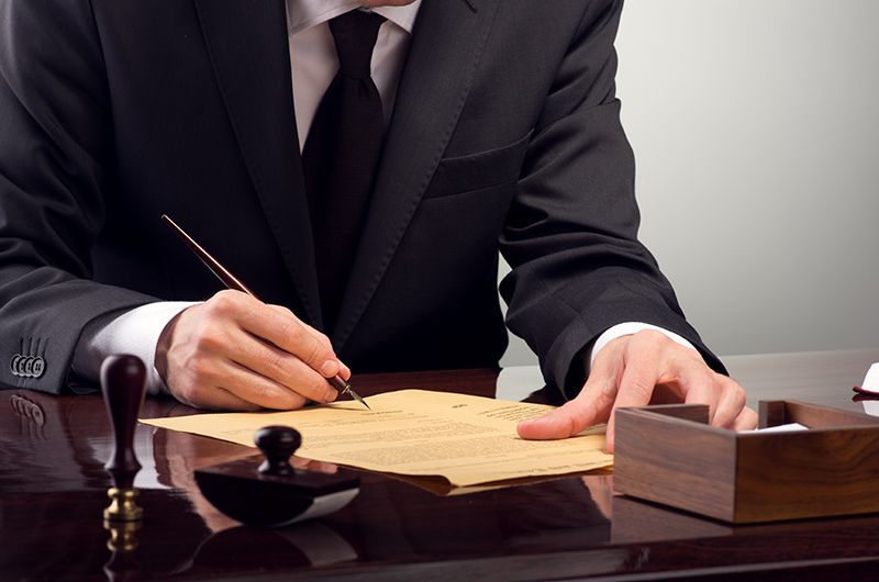 A man in a suit and tie is writing on a piece of paper
