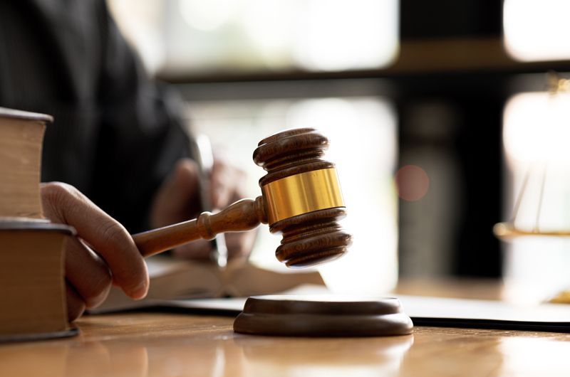 A judge is sitting at a table holding a wooden gavel.