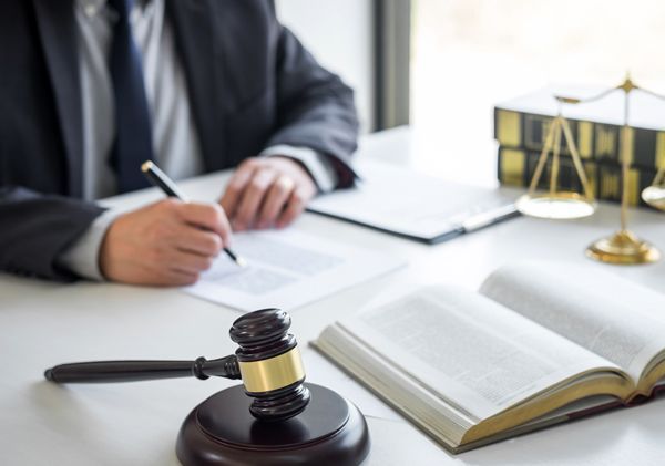 A judge is sitting at a desk with a book and a gavel.