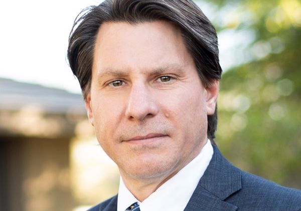 A man in a suit and tie is looking at the camera.