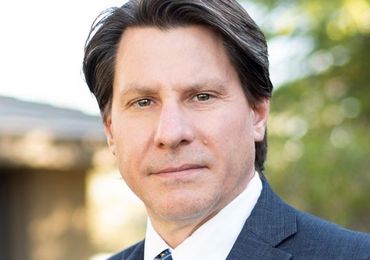 A man in a suit and tie is looking at the camera.