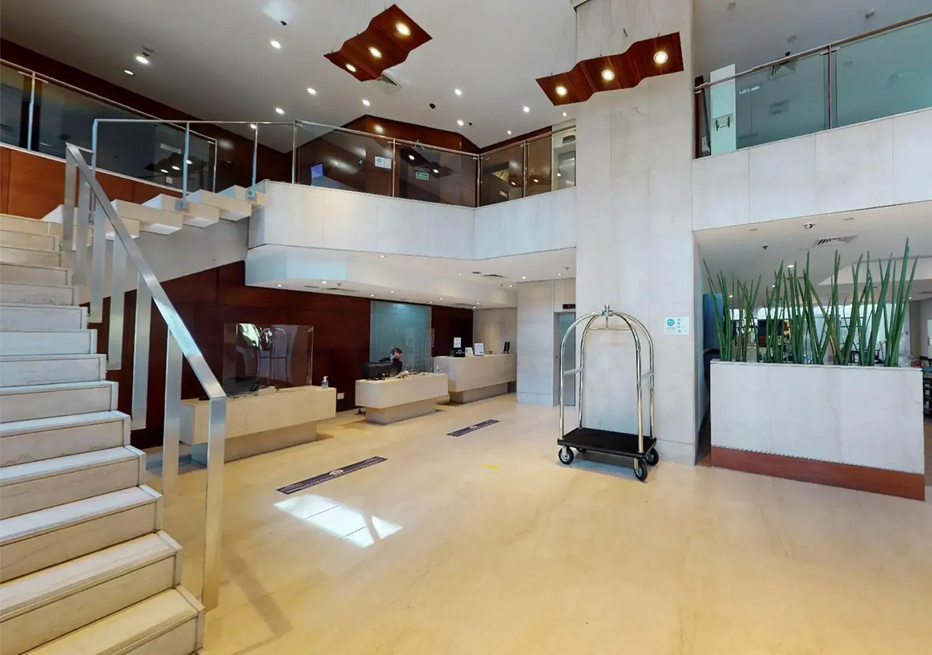 um lobby de hotel com escadas e carrinho de bagagem.