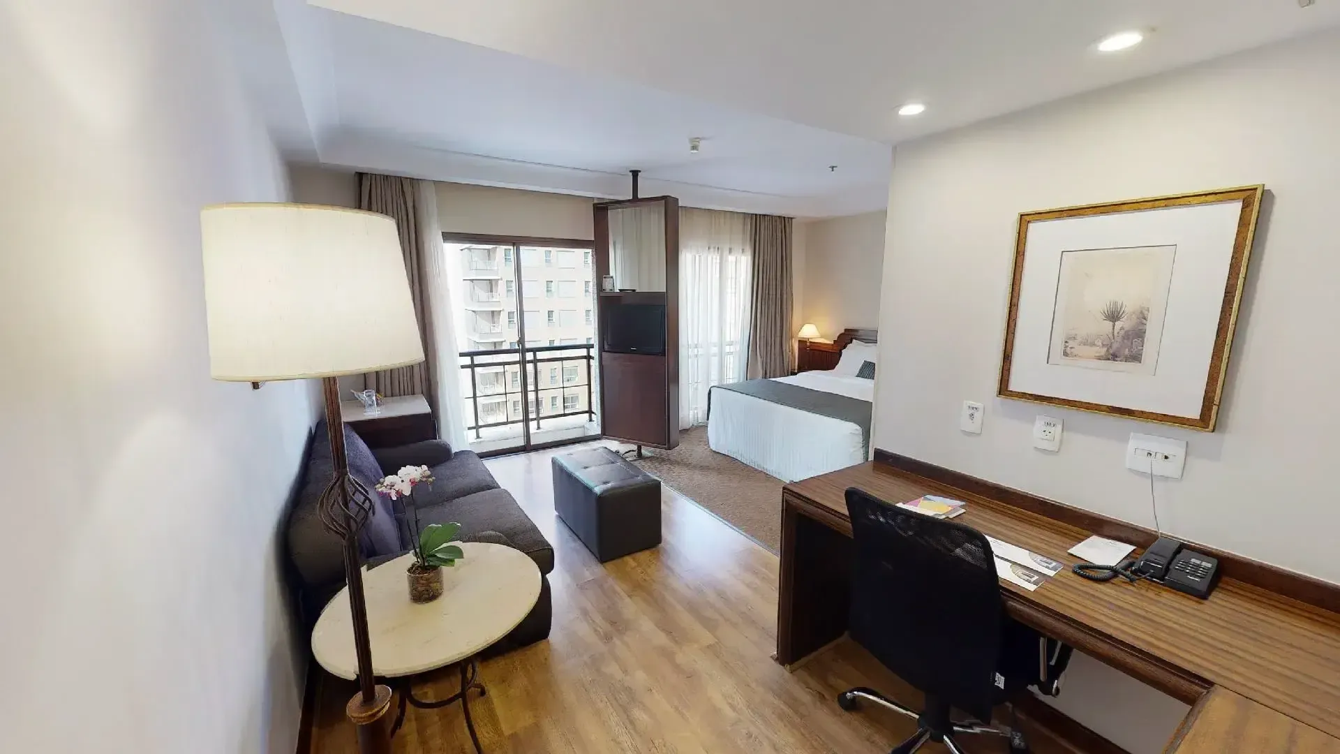 um quarto de hotel com sofá, mesa, cadeira e luminária.