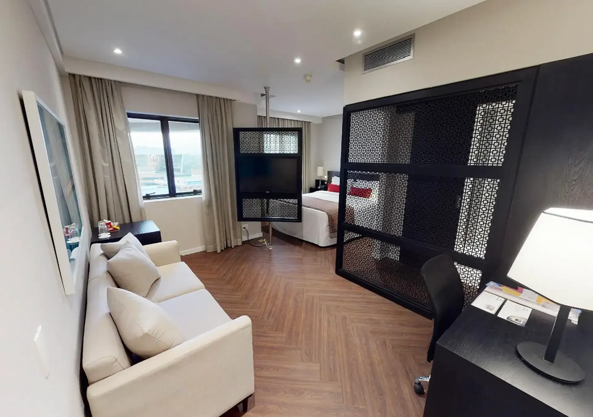 um quarto de hotel com sofá, mesa e televisão.