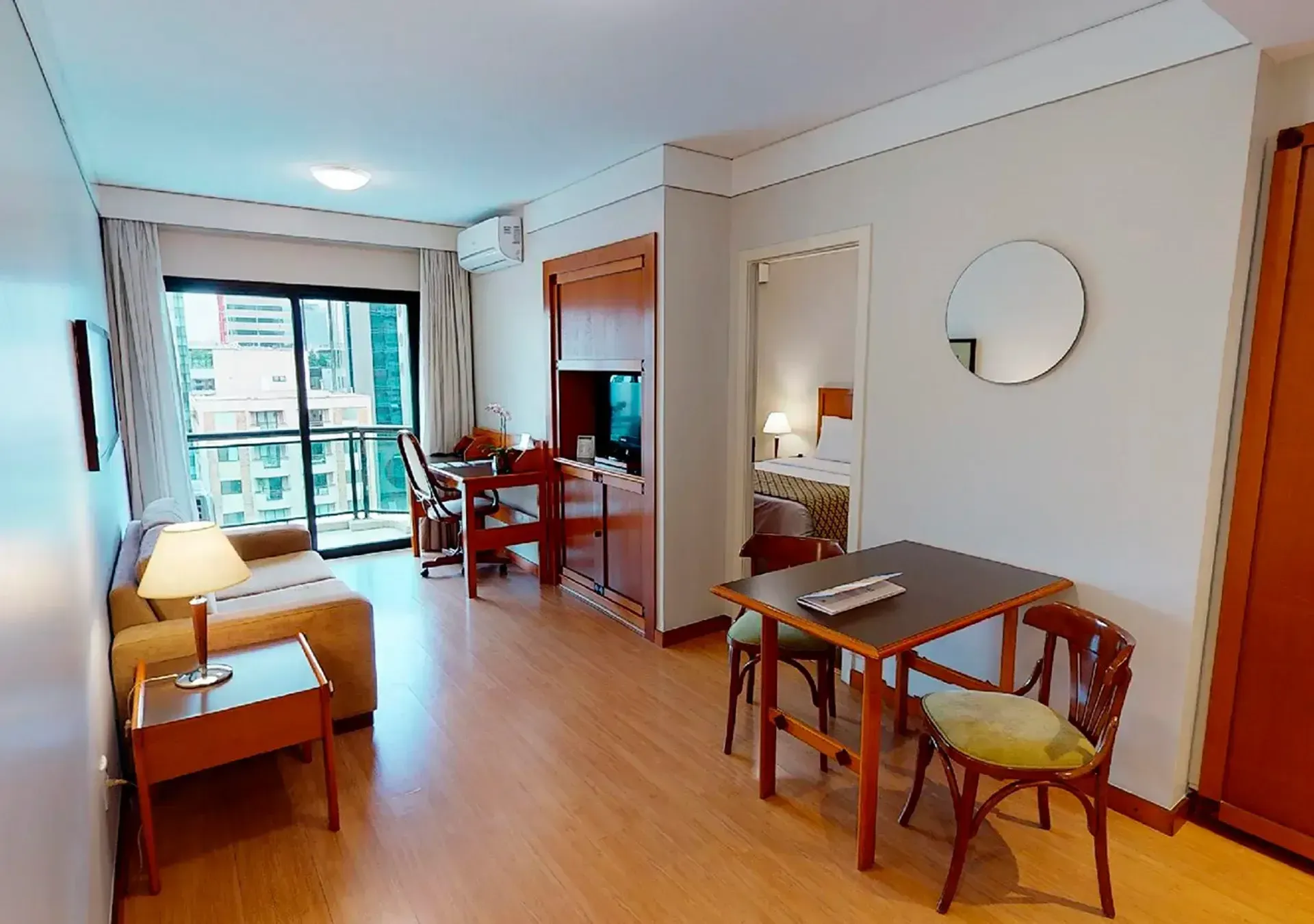uma sala com sofá, mesa, cadeiras e espelho.