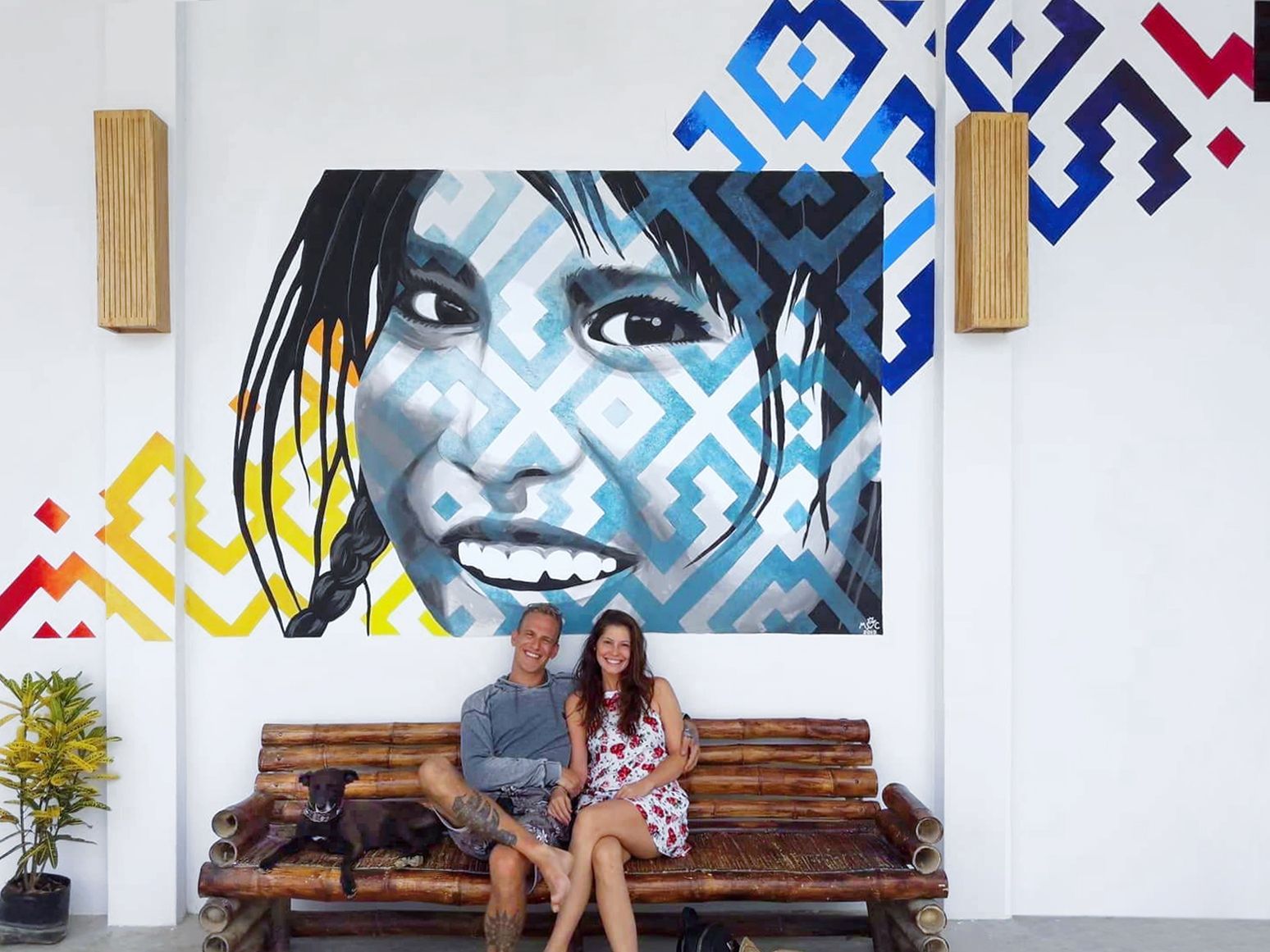Jens och Caroline Thor framför en stor muralmålning i deras karaktäristiska glada stil
