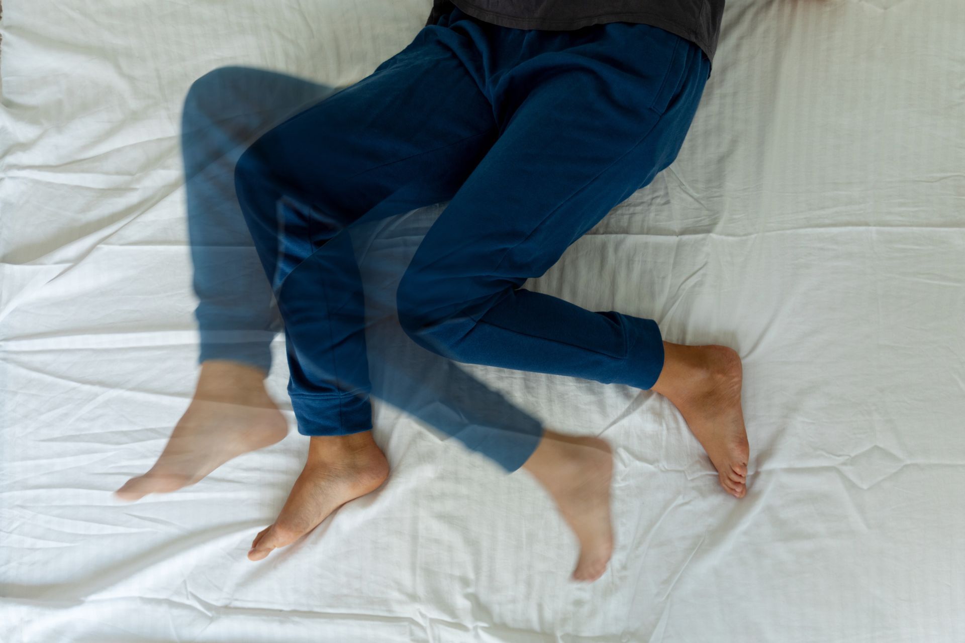A person is laying on a bed with their legs crossed.
