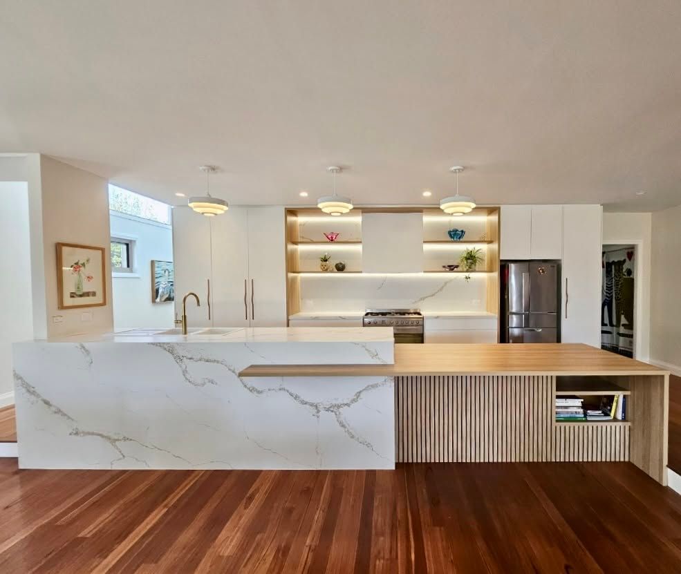 Modern White Kitchen with Marble Island, Wood Floors, Open Shelving, and Stainless Refrigerator — JDS Kitchens & Detailed Joinery in Albion Park Rail, NSW