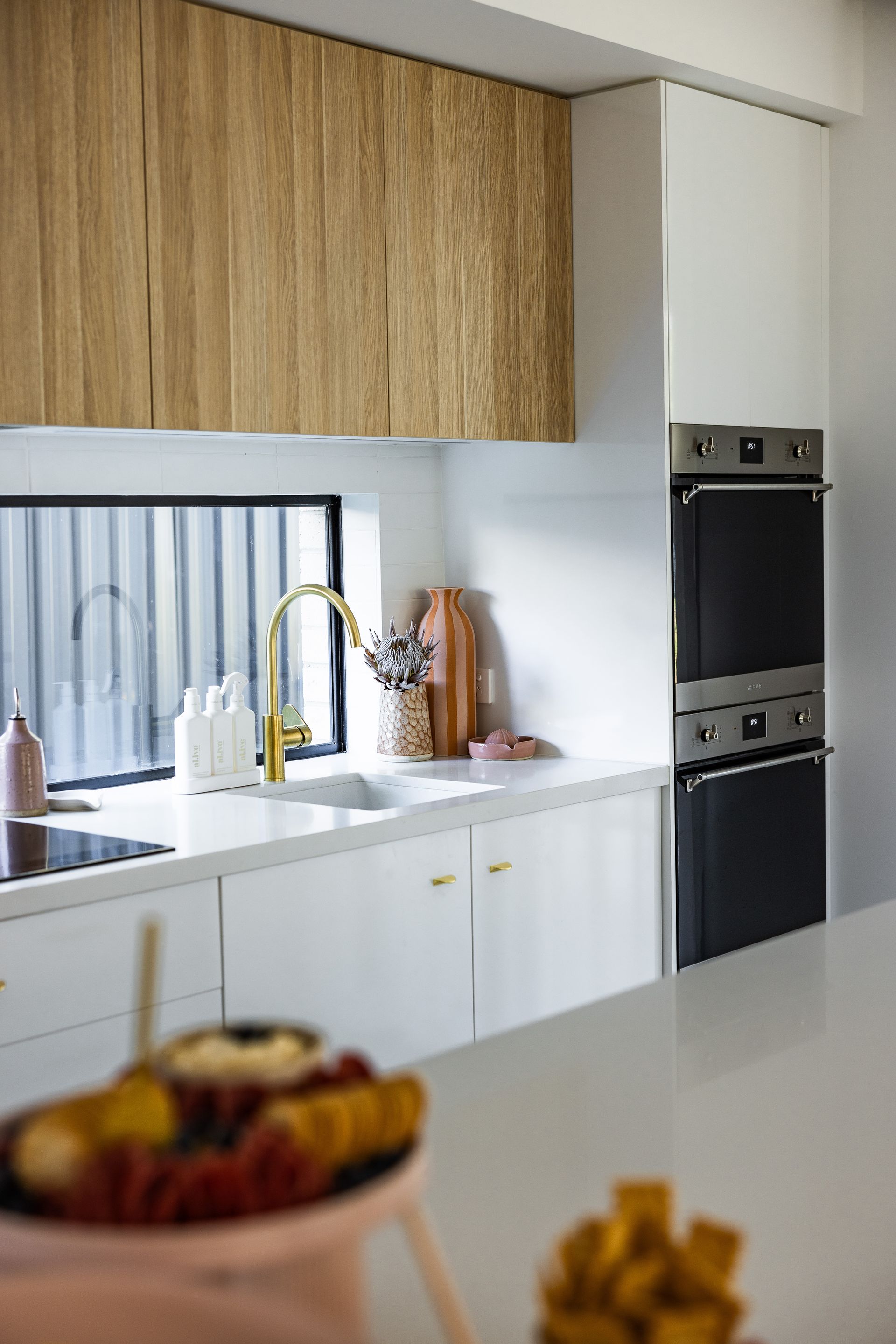 Modern Kitchen with White Cabinets, Wood Upper Cabinets, Built In Oven, and A Sink by A Window — JDS Kitchens & Detailed Joinery in Albion Park Rail, NSW