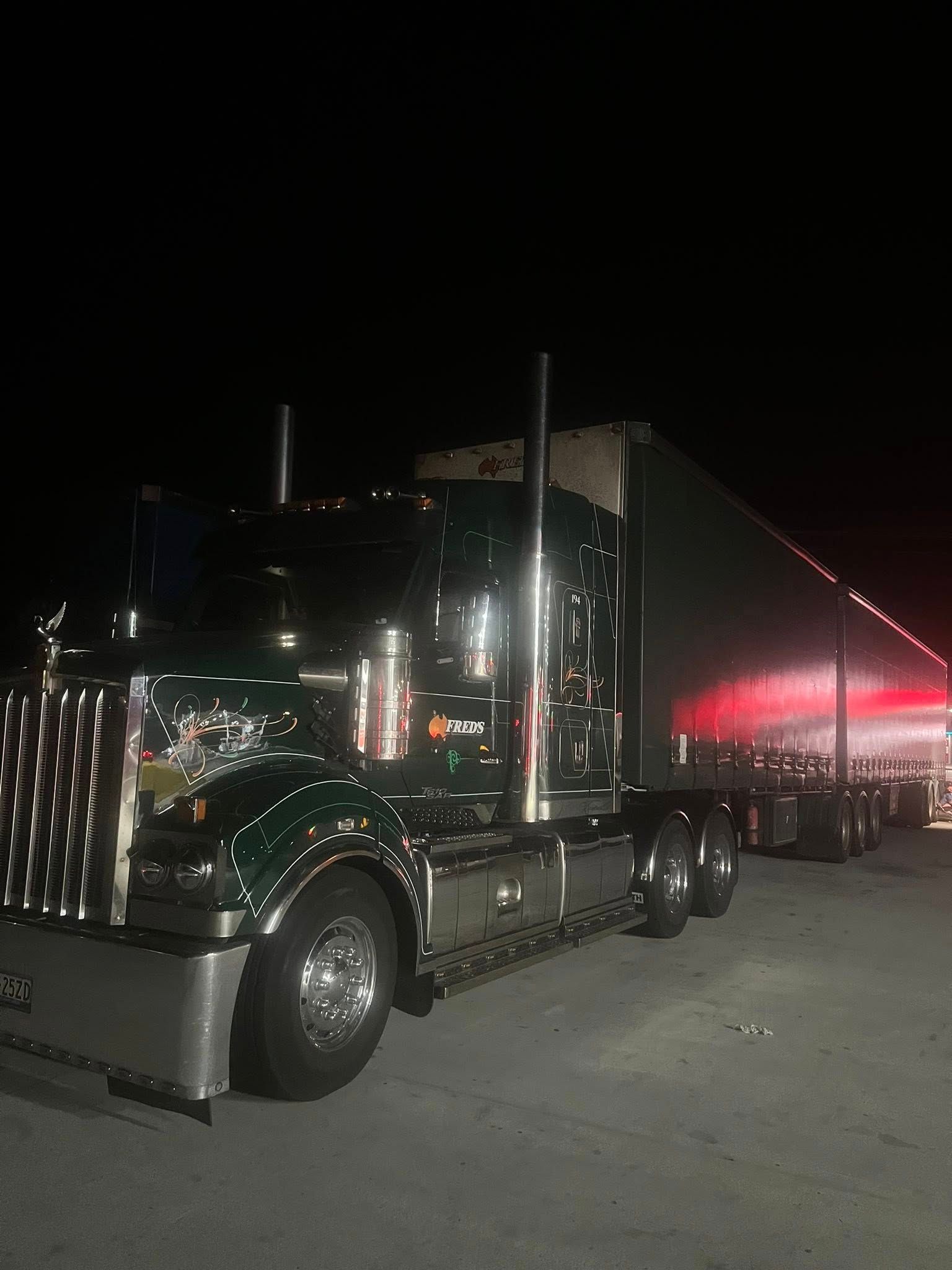Black Semi-truck Parked at Night With Red-lit Trailer in a Dark Lot — North Coast Heavy Diesel In Macksville, NSW