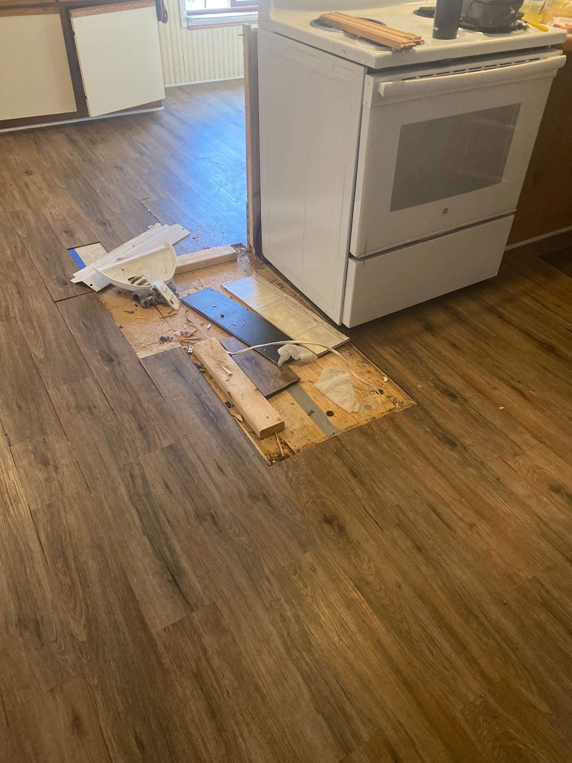A kitchen with a stove and a wooden floor getting replaced and fixed