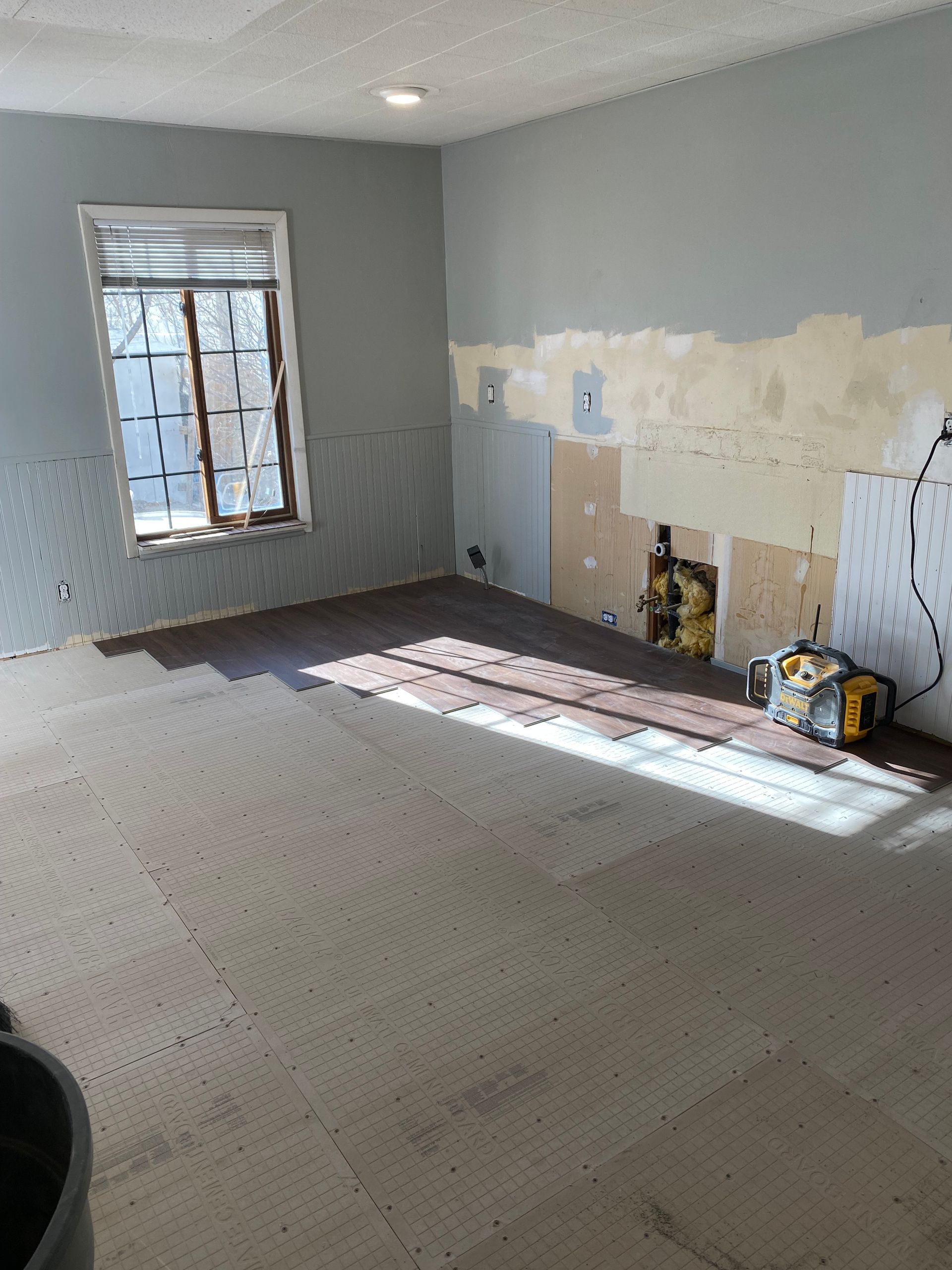 An empty room with a window and a vacuum cleaner on the floor.