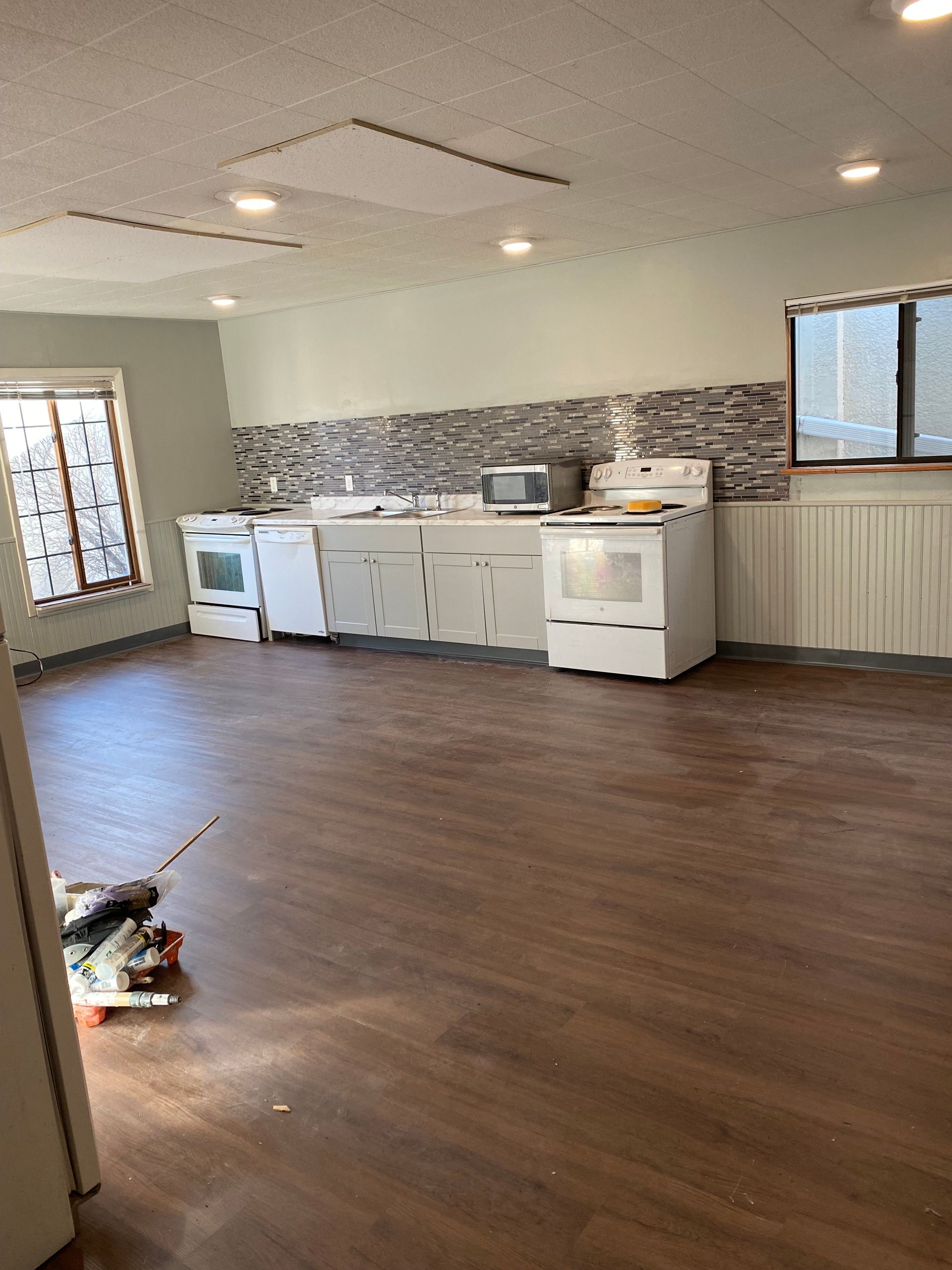 An empty kitchen with a wooden floor and a stove.
