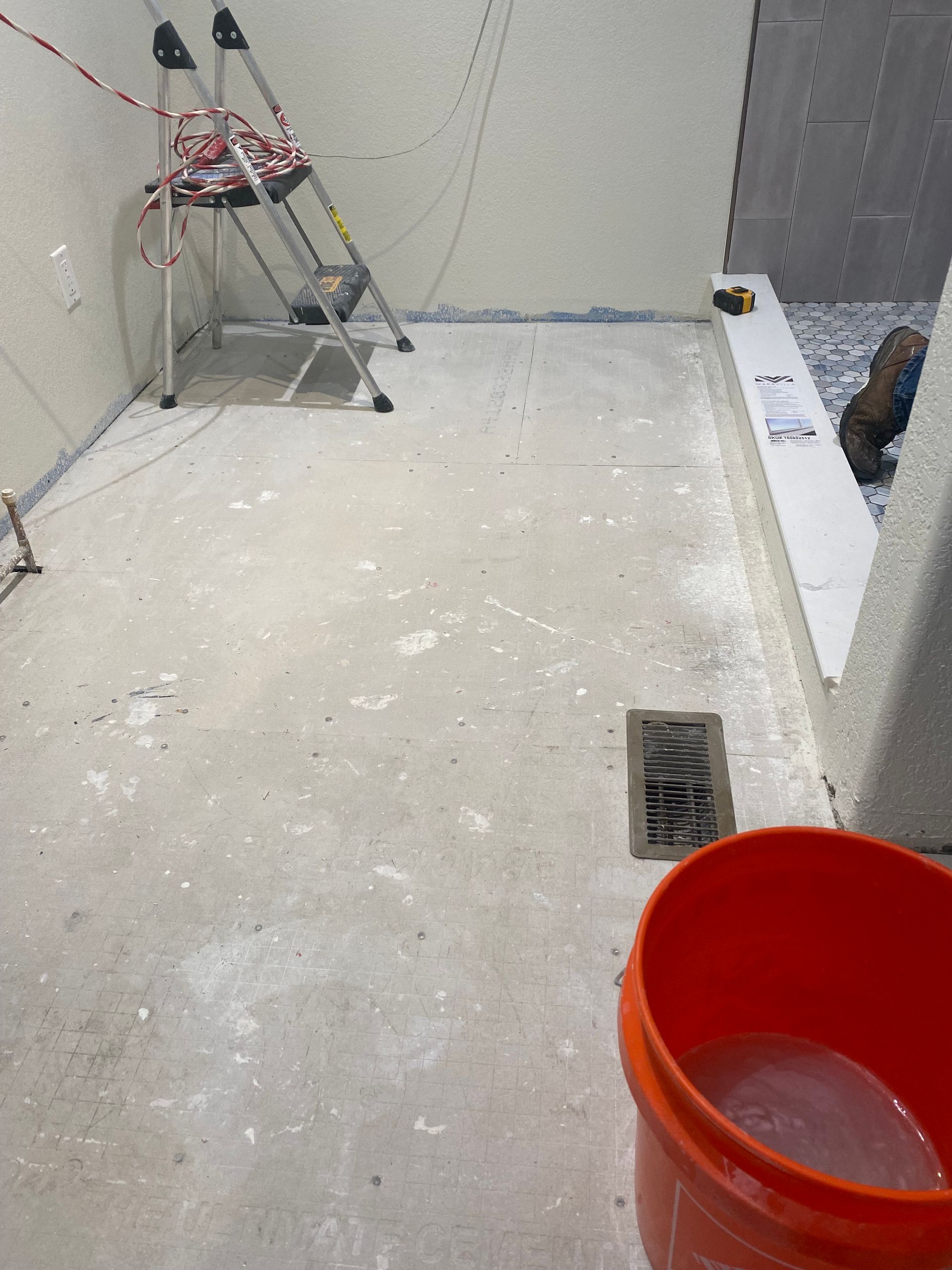 A bucket of water sits on the floor next to a ladder