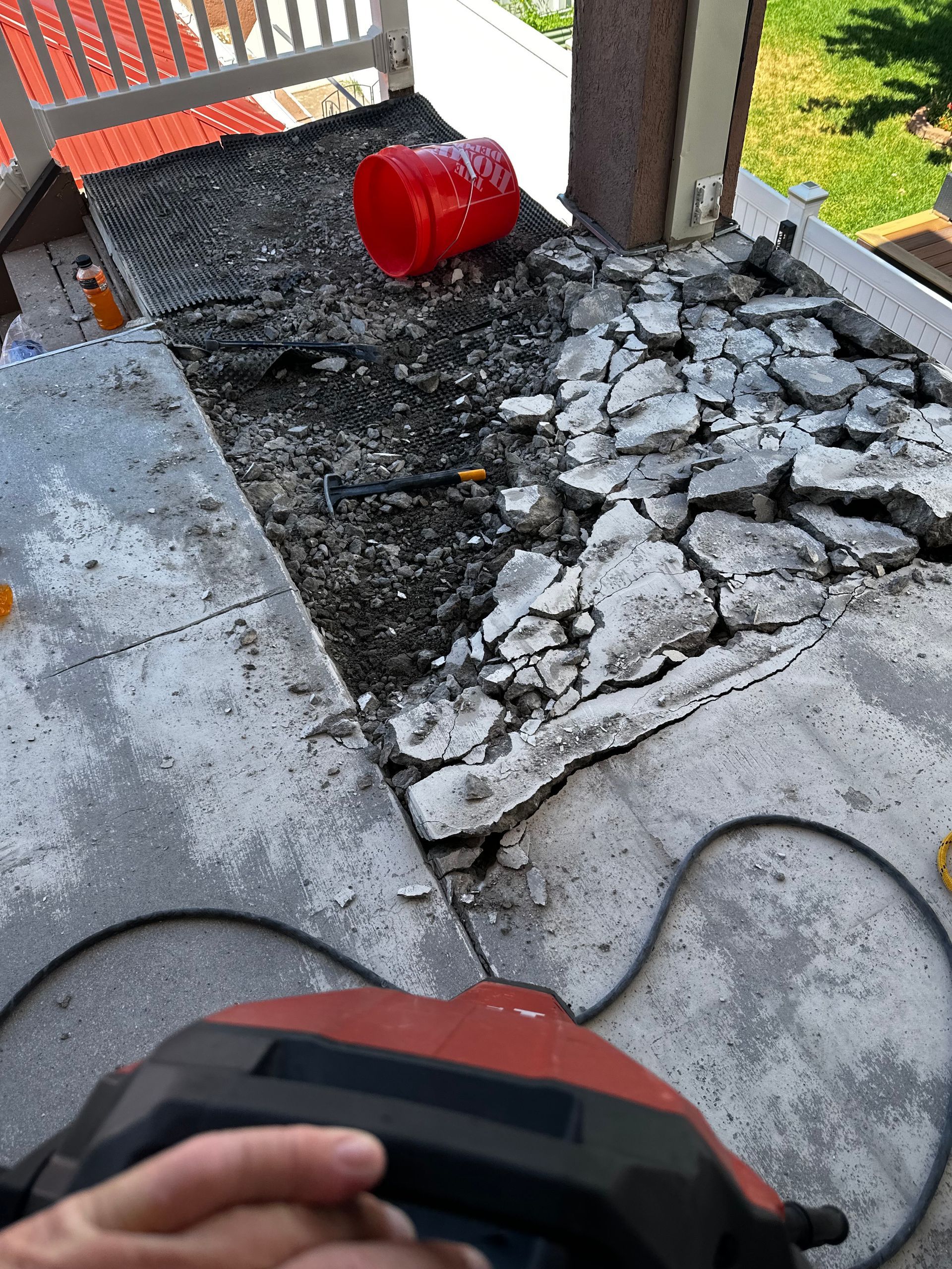 A person is using a vacuum cleaner on a concrete porch