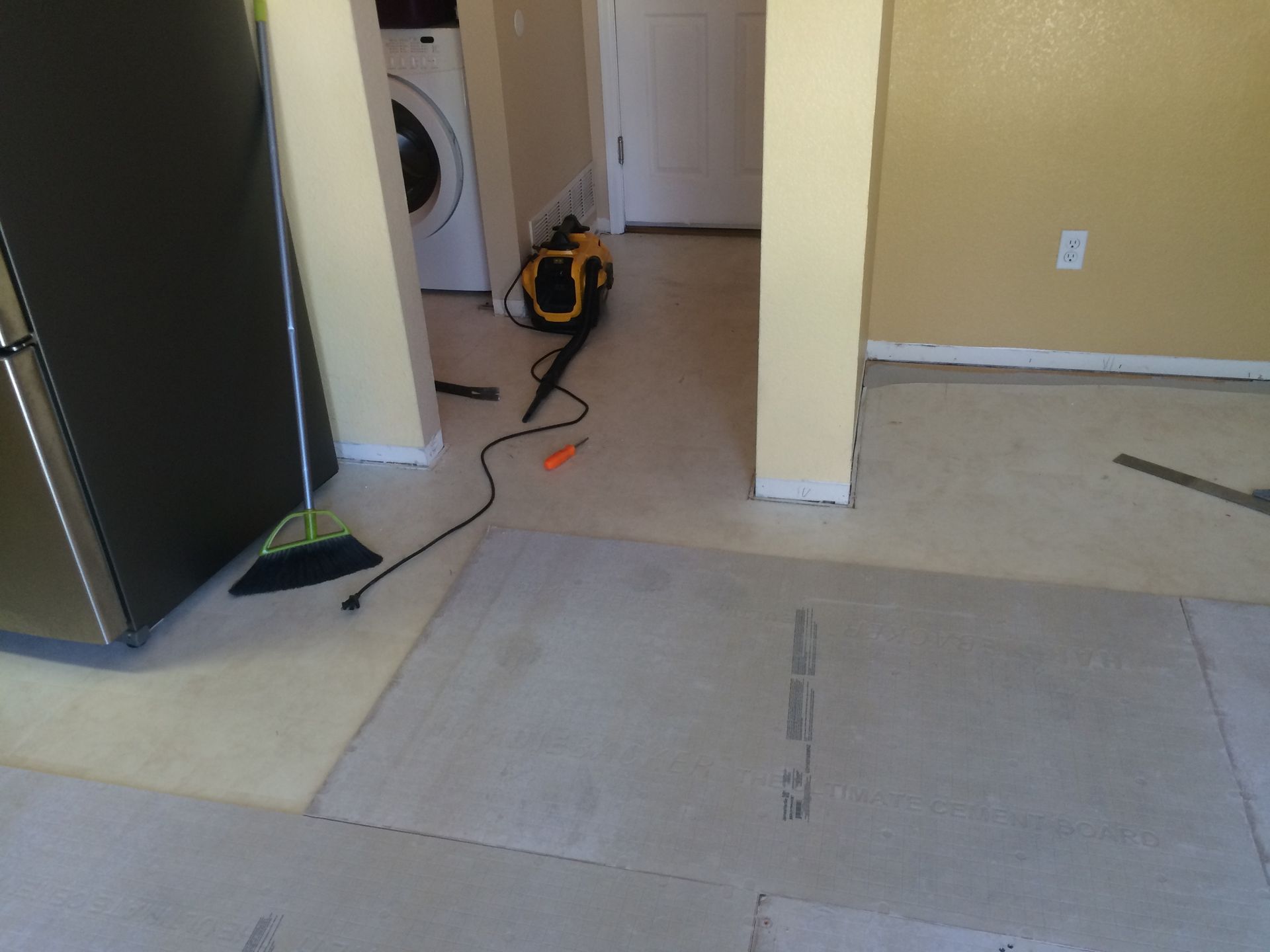 A broom is sitting on the floor next to a washer and dryer