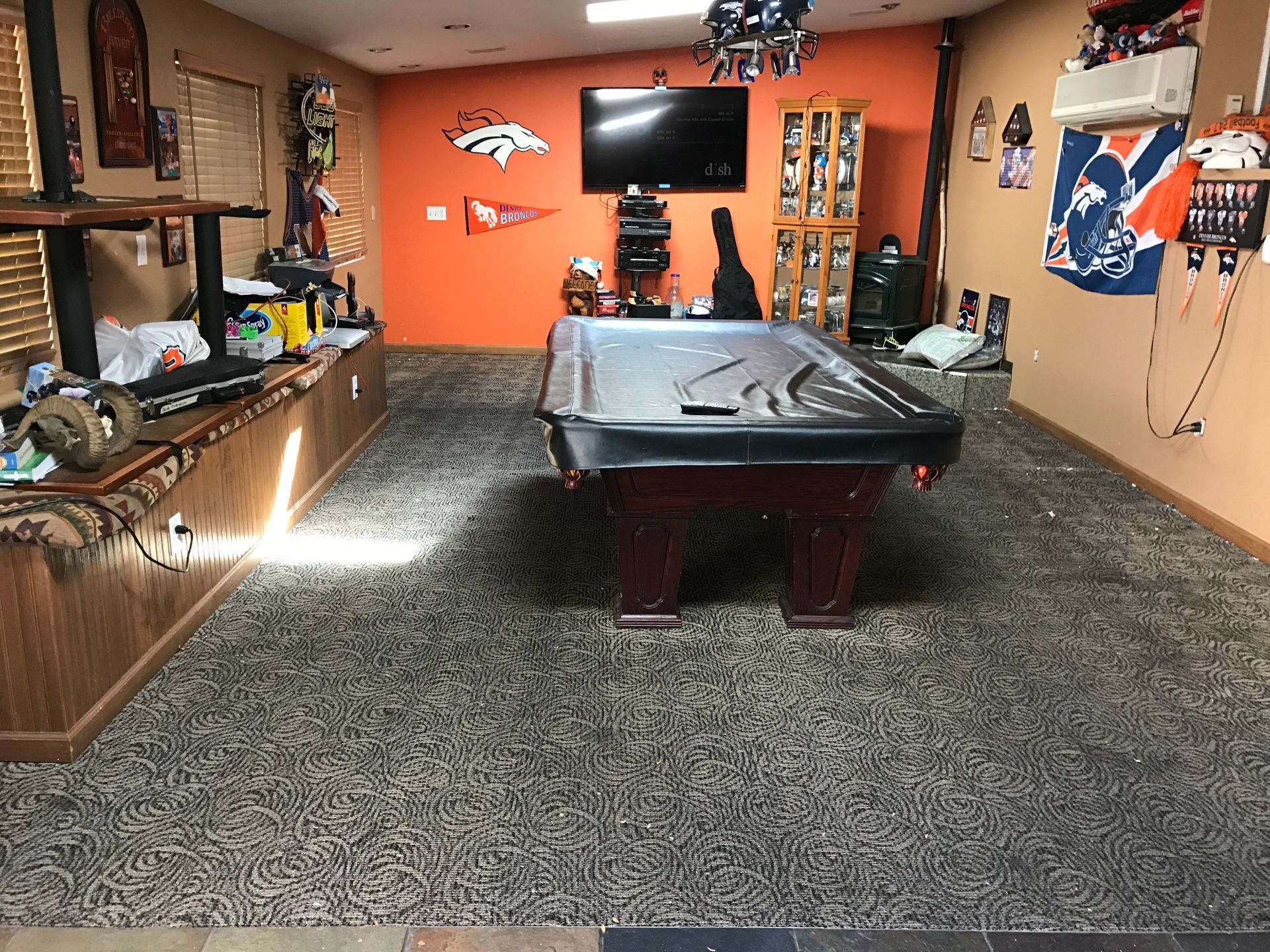 A pool table in a room with a tv on the wall. Before hardwood replacement