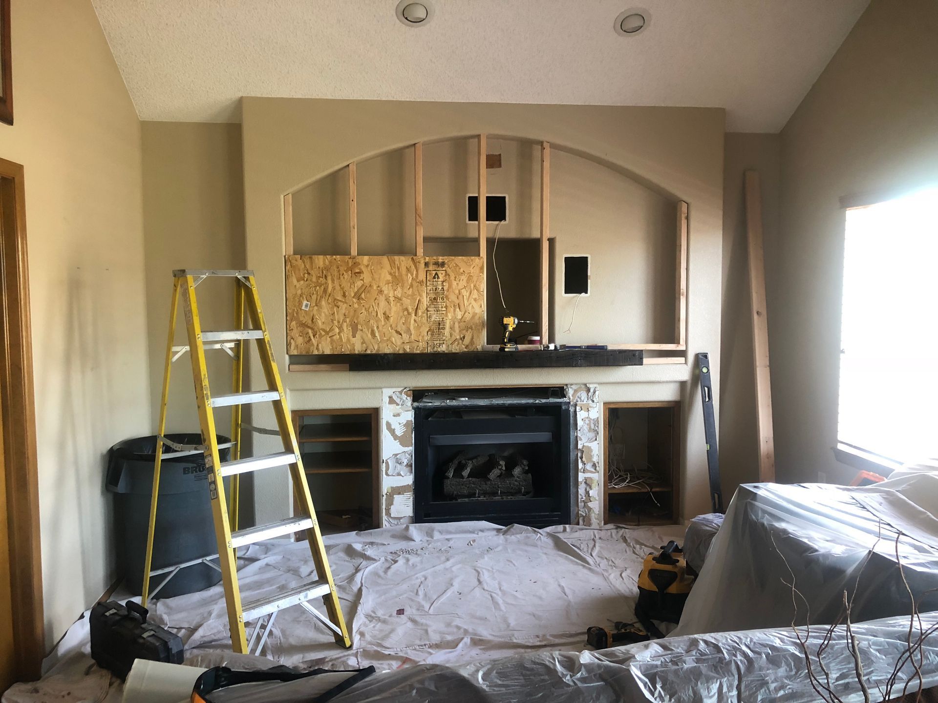 A living room with a fireplace and a ladder in it
