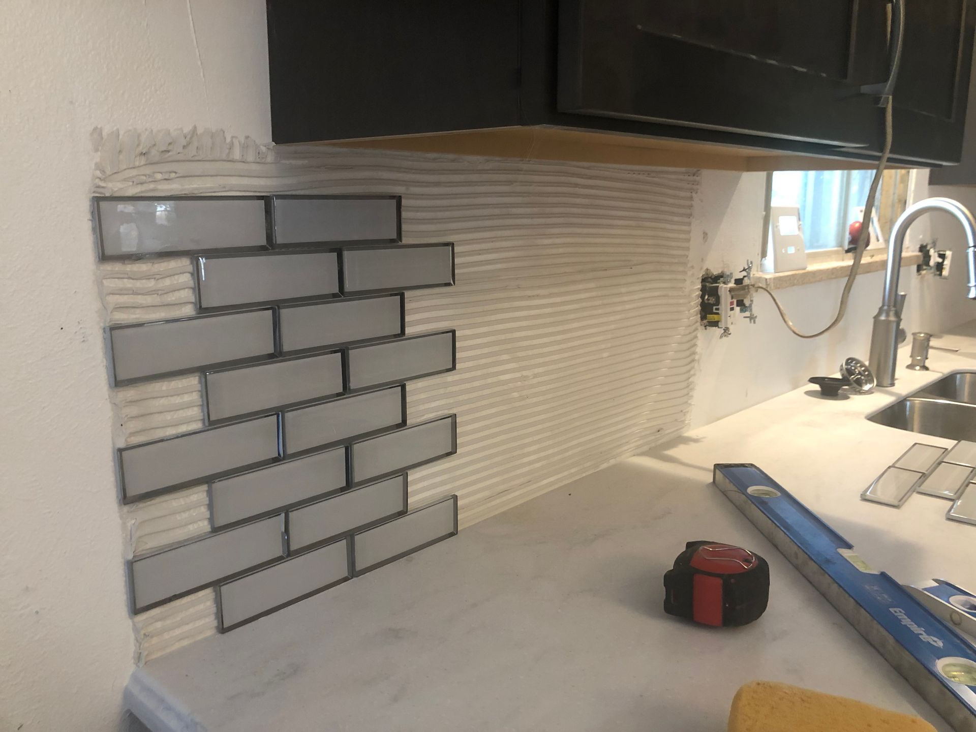 A kitchen with a brick wall and a measuring tape on the counter.