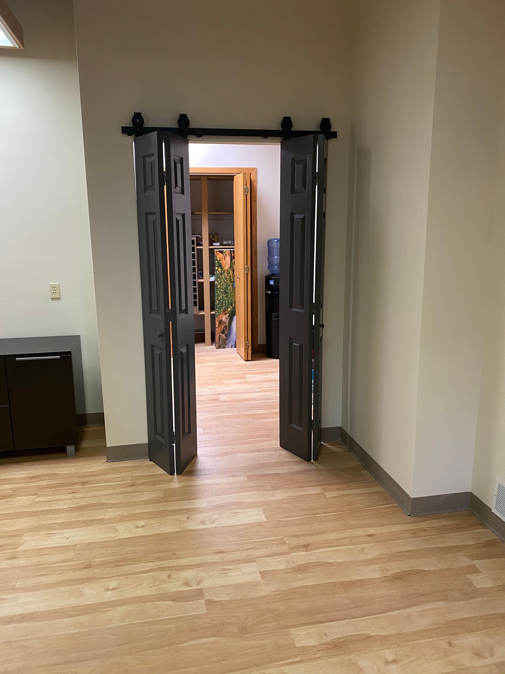 A room with wooden floors and sliding barn doors leading to a room.