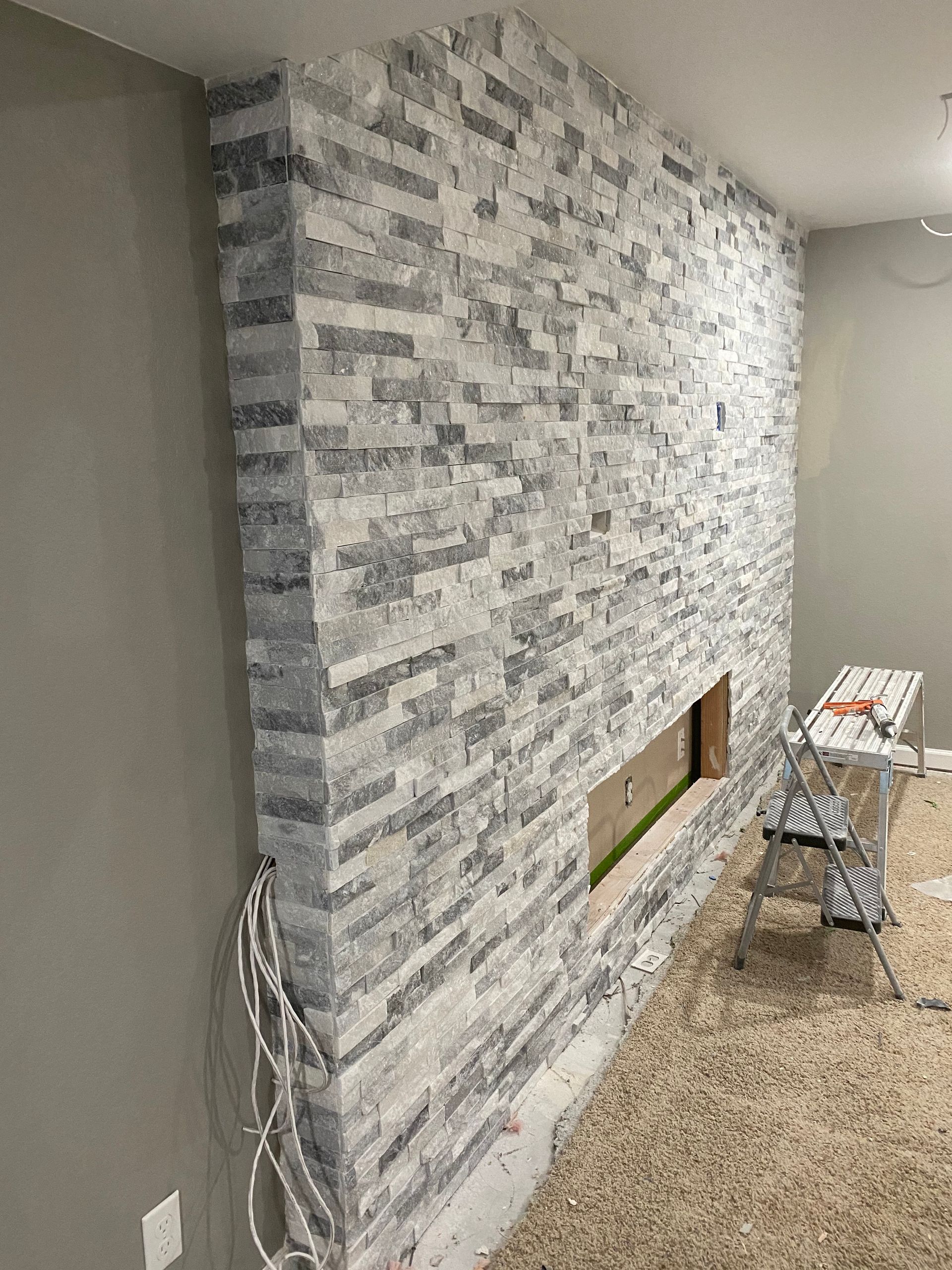 A fireplace is being built into a brick wall in a living room.