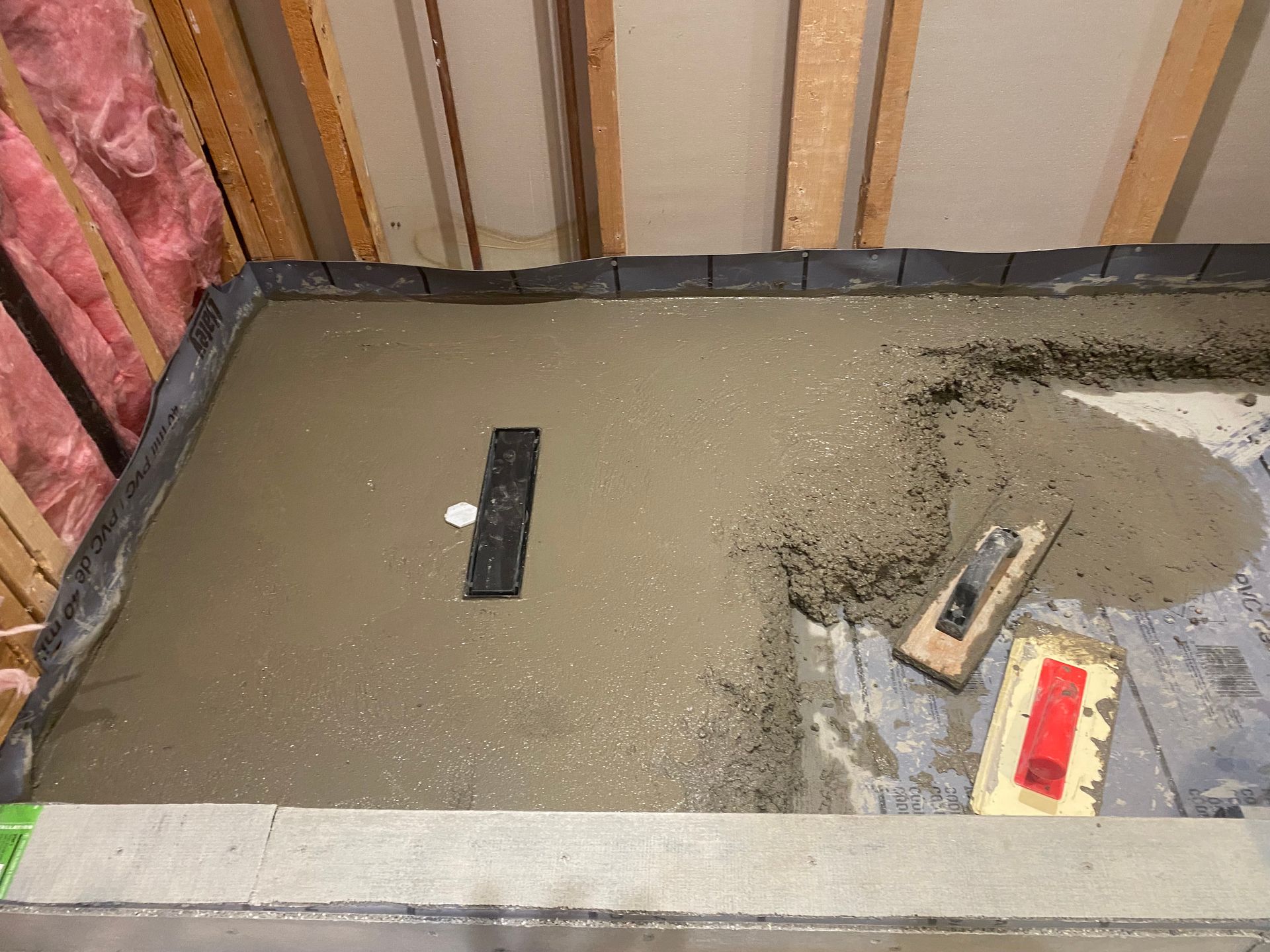 A concrete floor is being built in a room with tools on it.