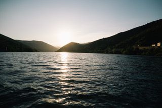 Golden hour sunset cruise on the Douro River with panoramic views of terraced vineyards.