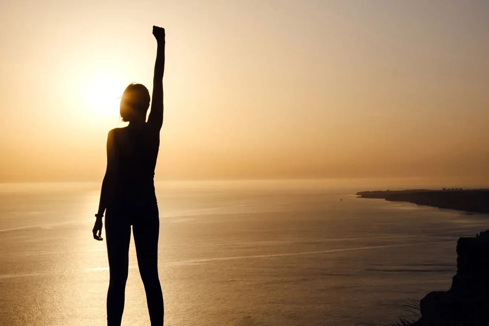 A women bringing hand up toward sun