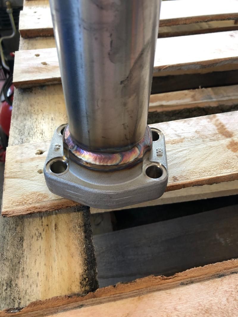Un tubo di metallo è appoggiato sopra un pallet di legno.