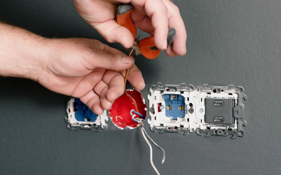 Hands repairing an exposed electrical device with wires and colorful internal parts