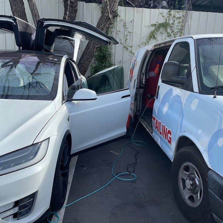 two white cars are parked next to a van that says talking