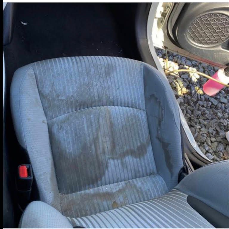 a dirty car seat in a car with the door open