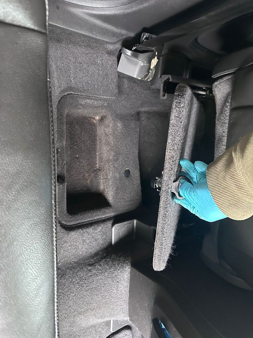 a person wearing blue gloves is opening the trunk of a car .