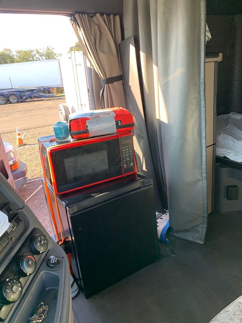 a red microwave sits on top of a black fridge