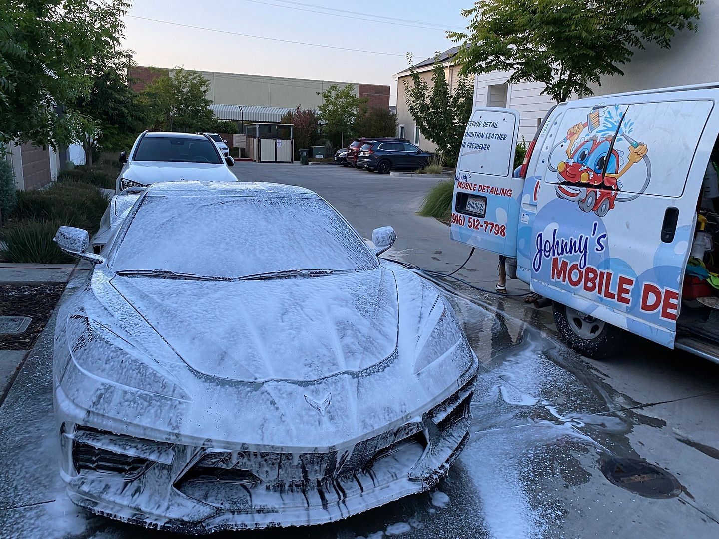 a car is covered in foam next to a van that says johnny 's mobile de .