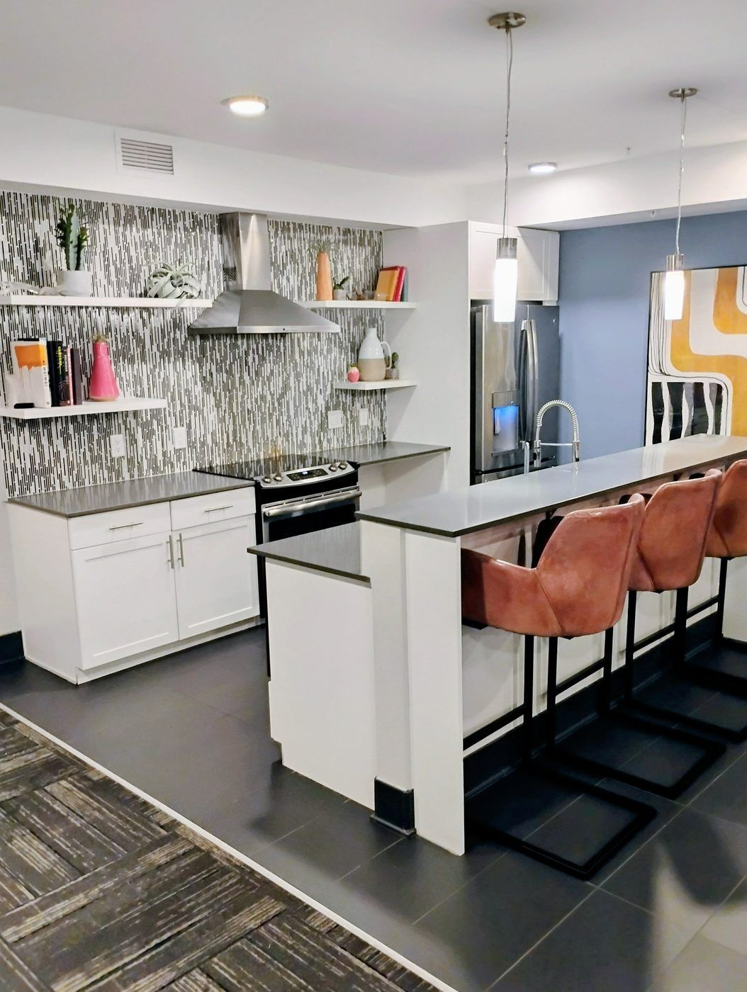 Modern kitchen with white cabinets, black countertops, island seating, and patterned backsplash