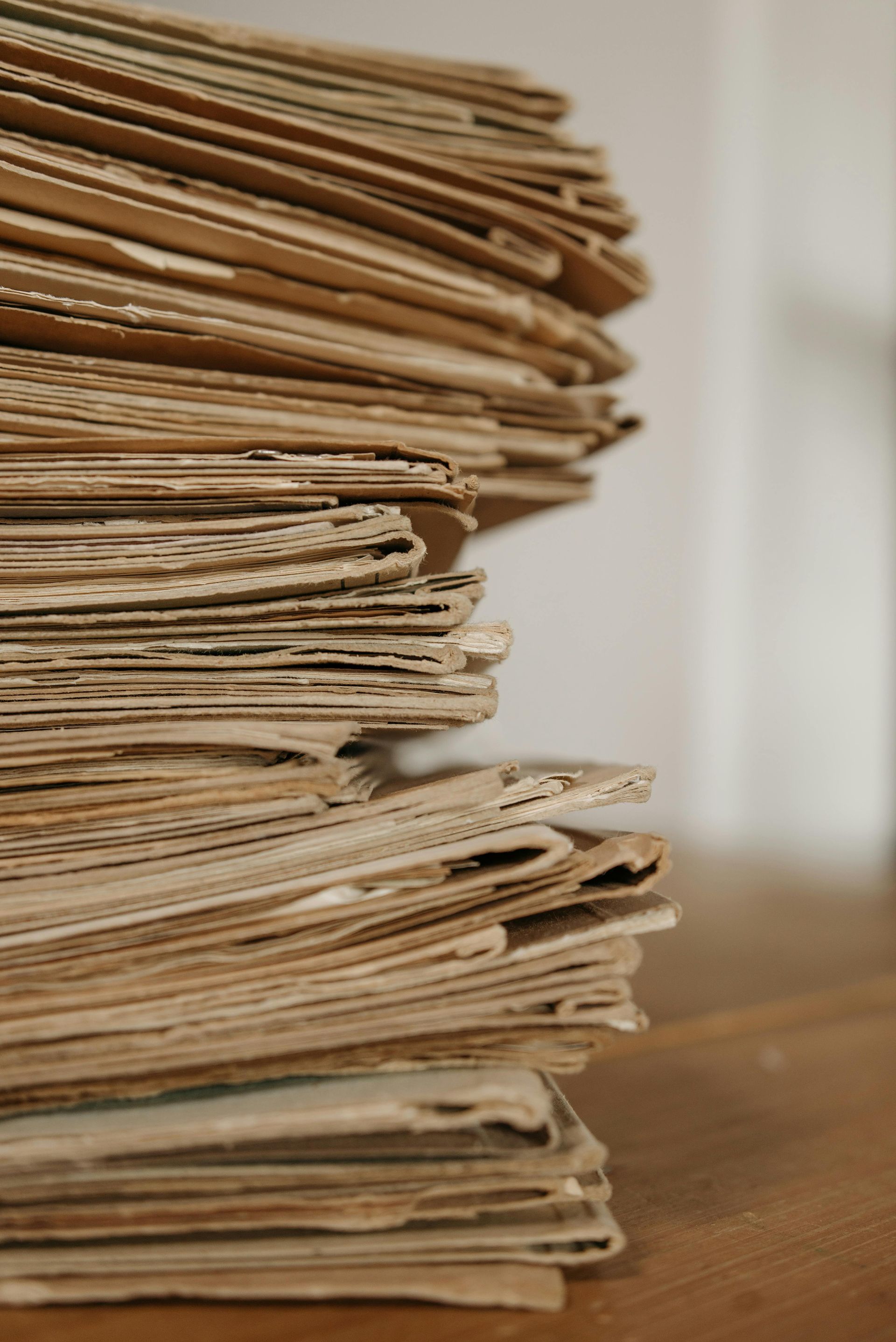 Stack of aged, brown papers on a wooden surface, likely documents or records.