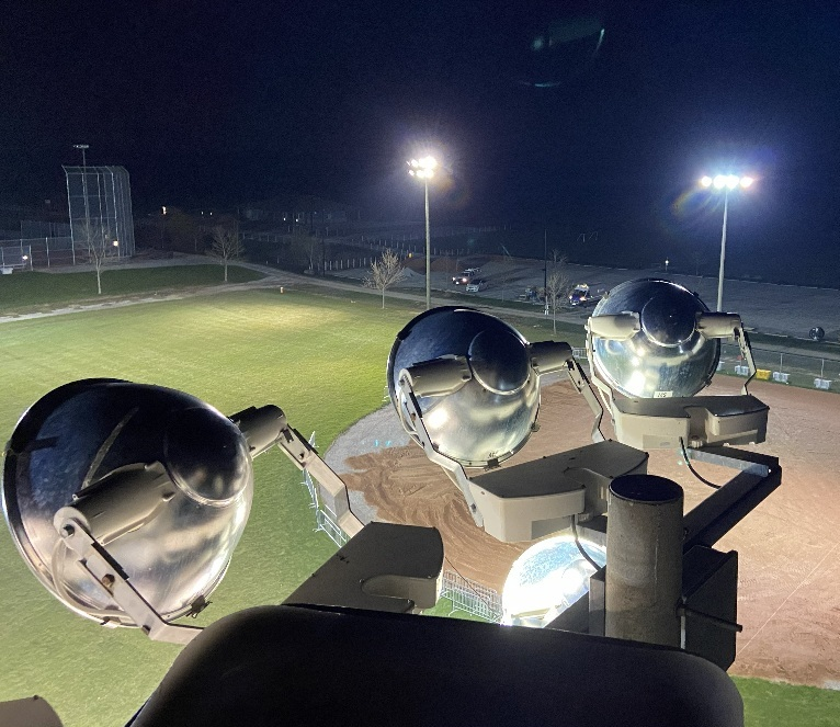 Shiny silver organ pipes overlooking a lit sports field at night