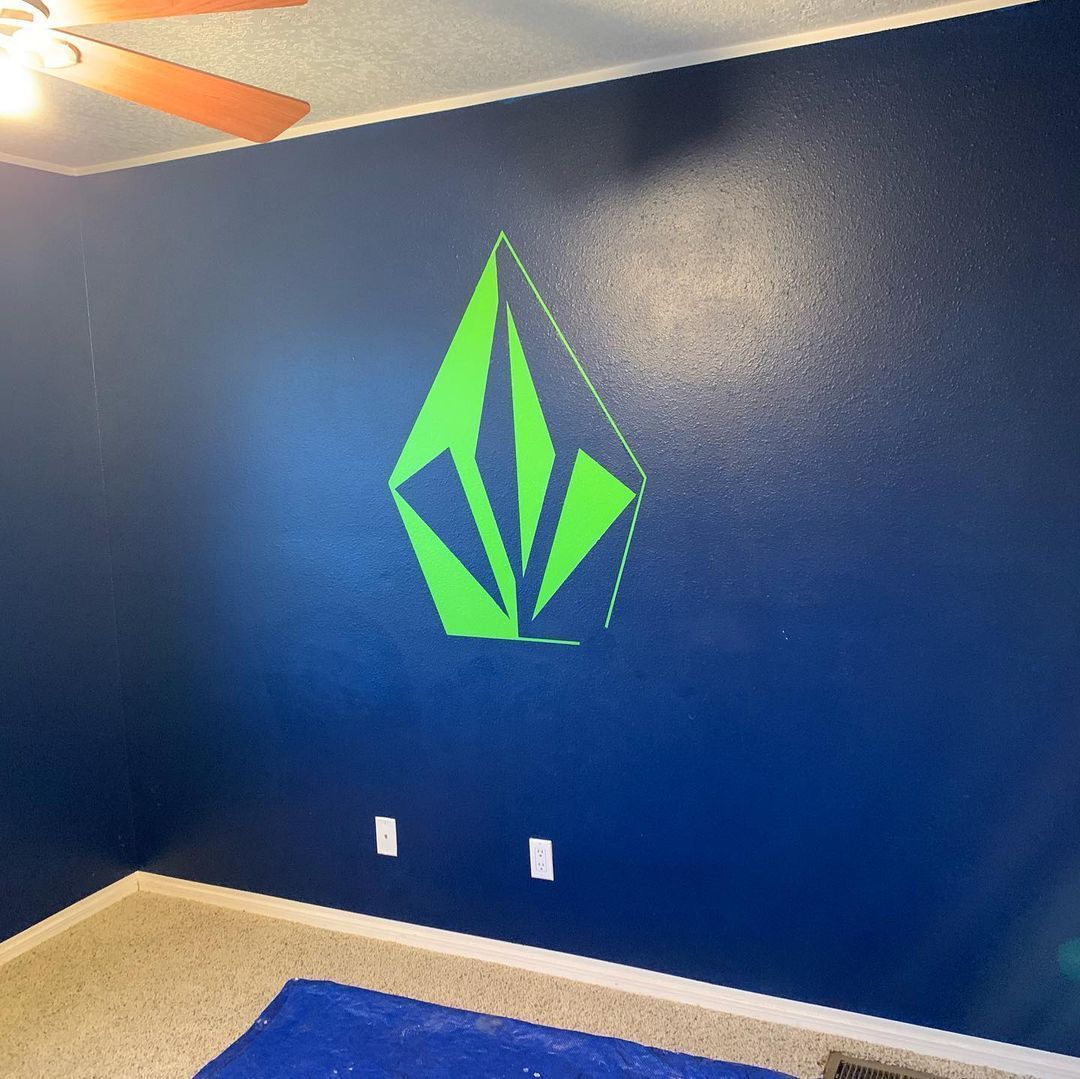Blue room wall with a bright green geometric emblem and white electrical outlets near the floor.