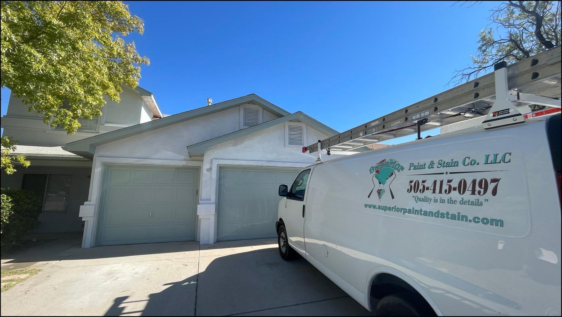 White service van parked outside a suburban garage under a bright blue sky