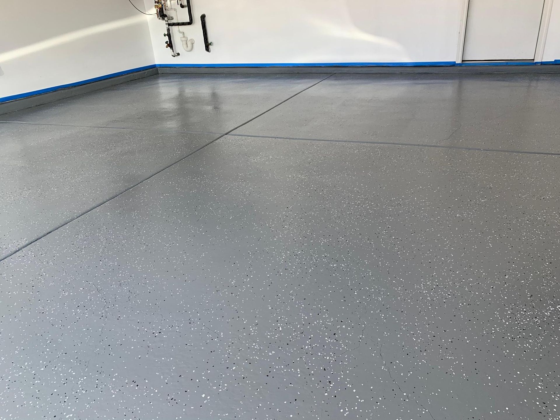 Empty gray speckled floor in a room with white walls and blue trim and baseboard