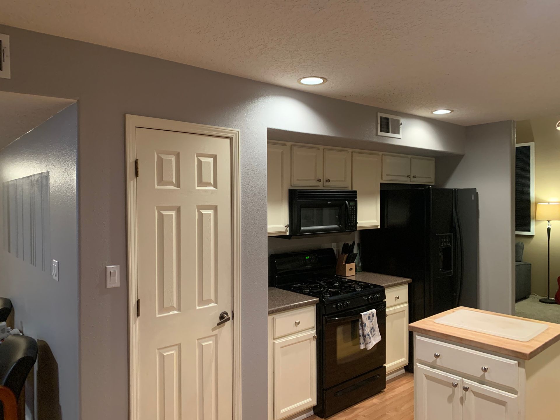 Modern kitchen with white cabinets, black appliances, and a small island under recessed ceiling lights