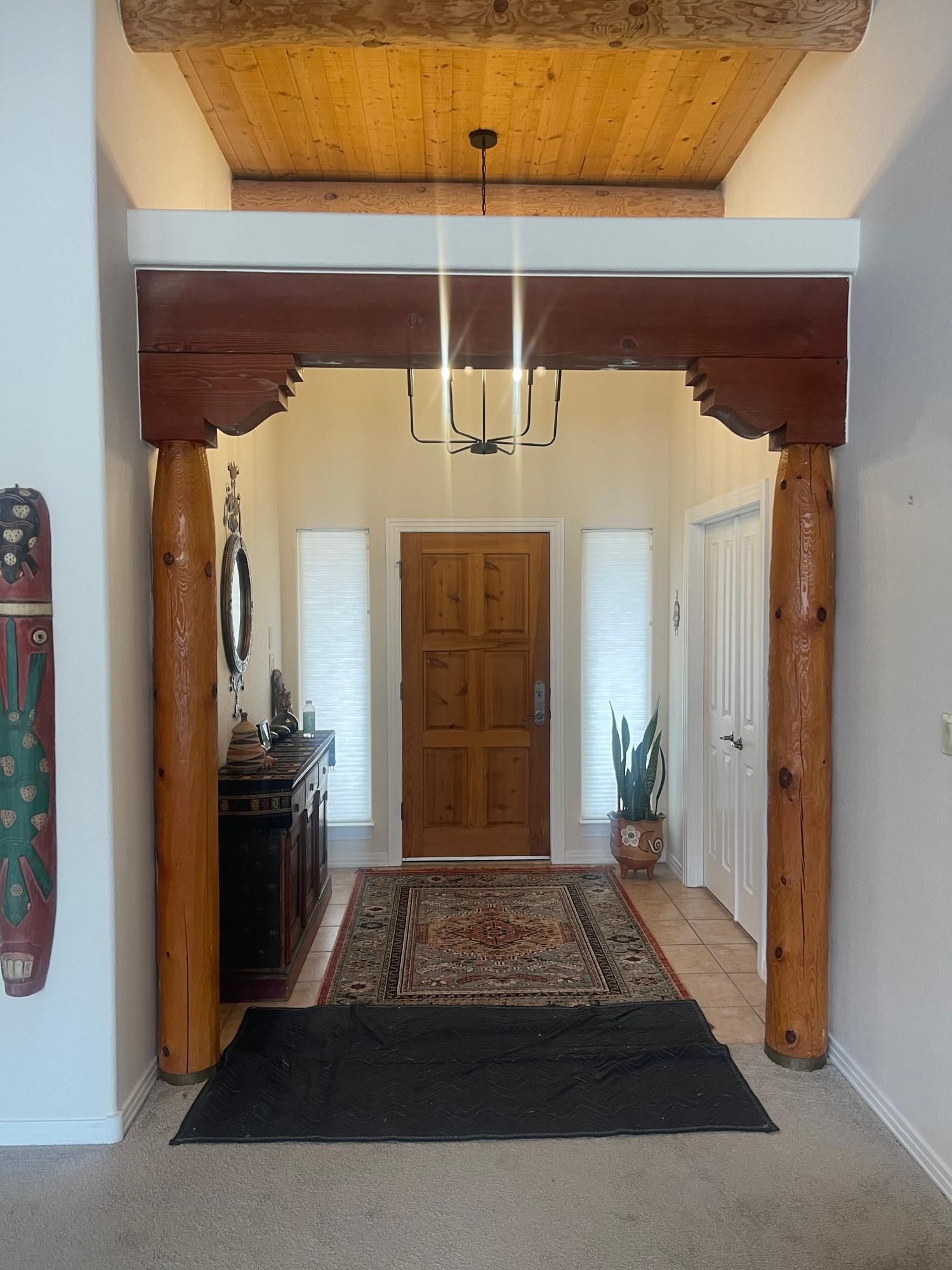 Wooden entry hall with carved posts, hanging light, and a runner leading to a front door