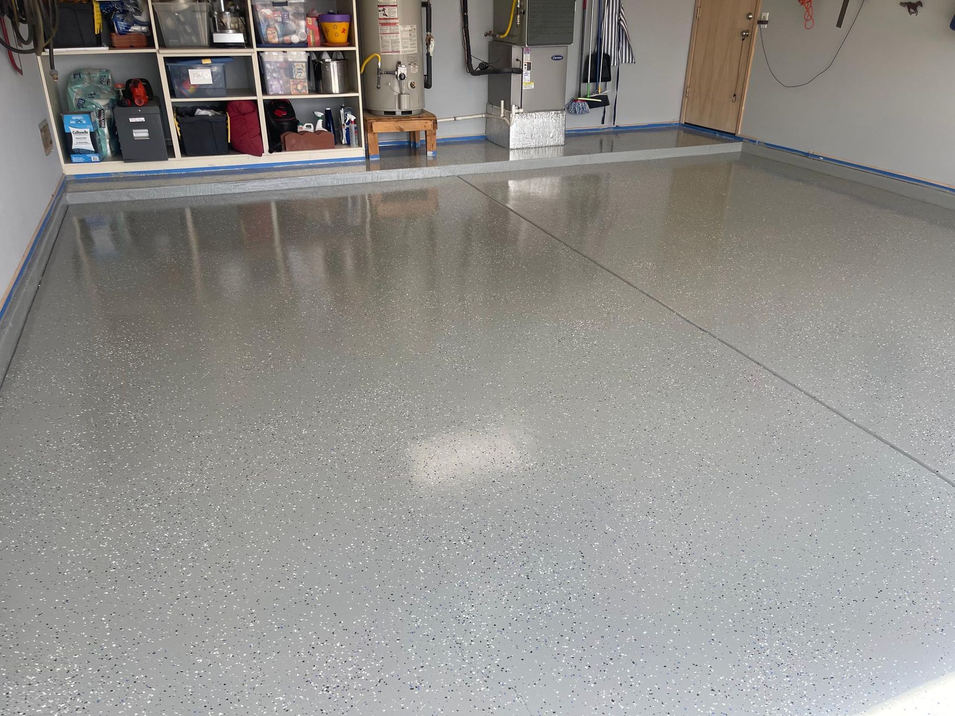 Empty epoxy-floored garage with shelves and tools along the back wall